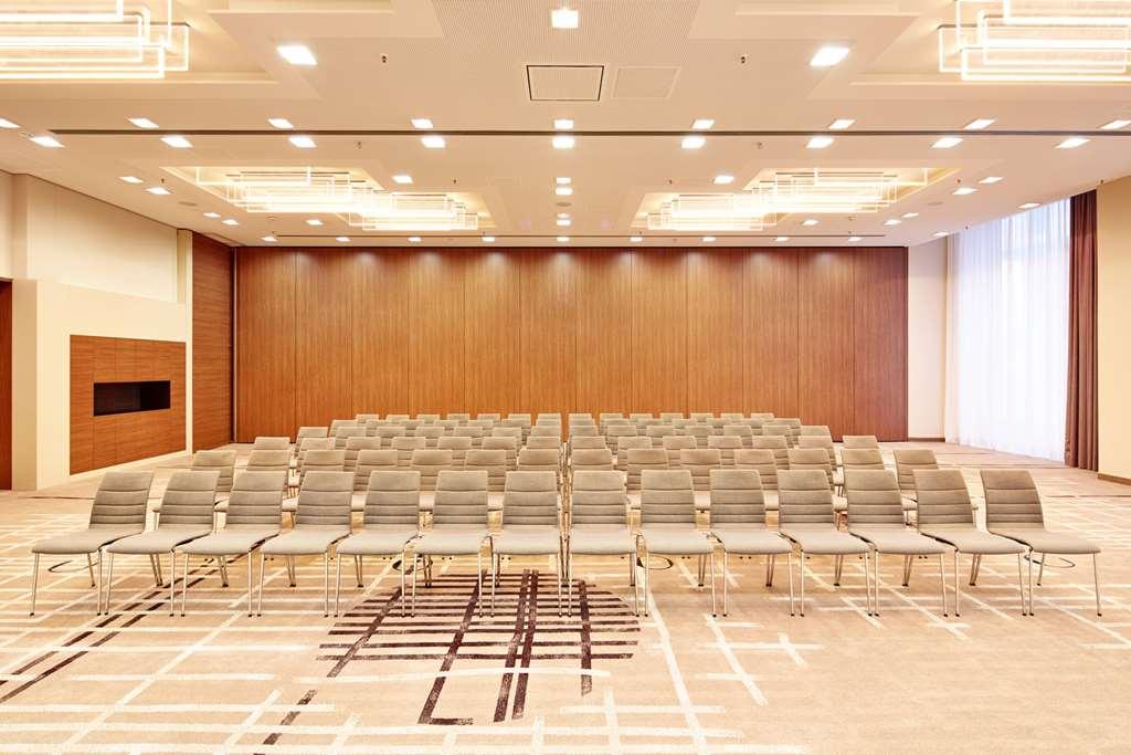 Steigenberger Hotel Am Kanzleramt Βερολίνο Ανέσεις φωτογραφία The photo shows a spacious conference room set up for an event or meeting. There are several rows of neatly arranged chairs facing a wall, indicating an audience setup. The room features a wood-paneled back wall, large windows allowing natural light,