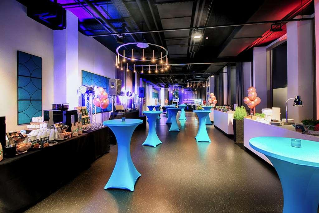 Steigenberger Hotel Am Kanzleramt Βερολίνο Ανέσεις φωτογραφία The photo shows a stylish event space, likely set up for a party or reception. The room features modern decor with a combination of colorful lighting, including purple and blue hues. There are several high-top tables covered with blue tablecloths, wh