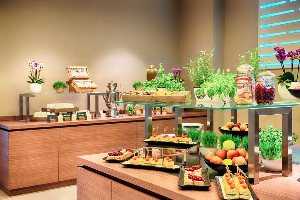 Steigenberger Hotel Am Kanzleramt Βερολίνο Ανέσεις φωτογραφία The photo depicts a modern buffet setup featuring an array of food items. It includes:

- Several rectangular platters displaying various appetizers, likely including hors d'oeuvres or small snacks.
- Fresh fruits such as apples and possibly other se