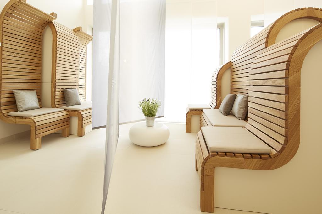 Steigenberger Hotel Am Kanzleramt Βερολίνο Εξωτερικό φωτογραφία The photo shows a modern, minimalistic interior space with a serene atmosphere. There are two wooden benches with a slatted design, featuring soft cushions for comfort. A small, round white coffee table sits in the center, and a green plant in a vase