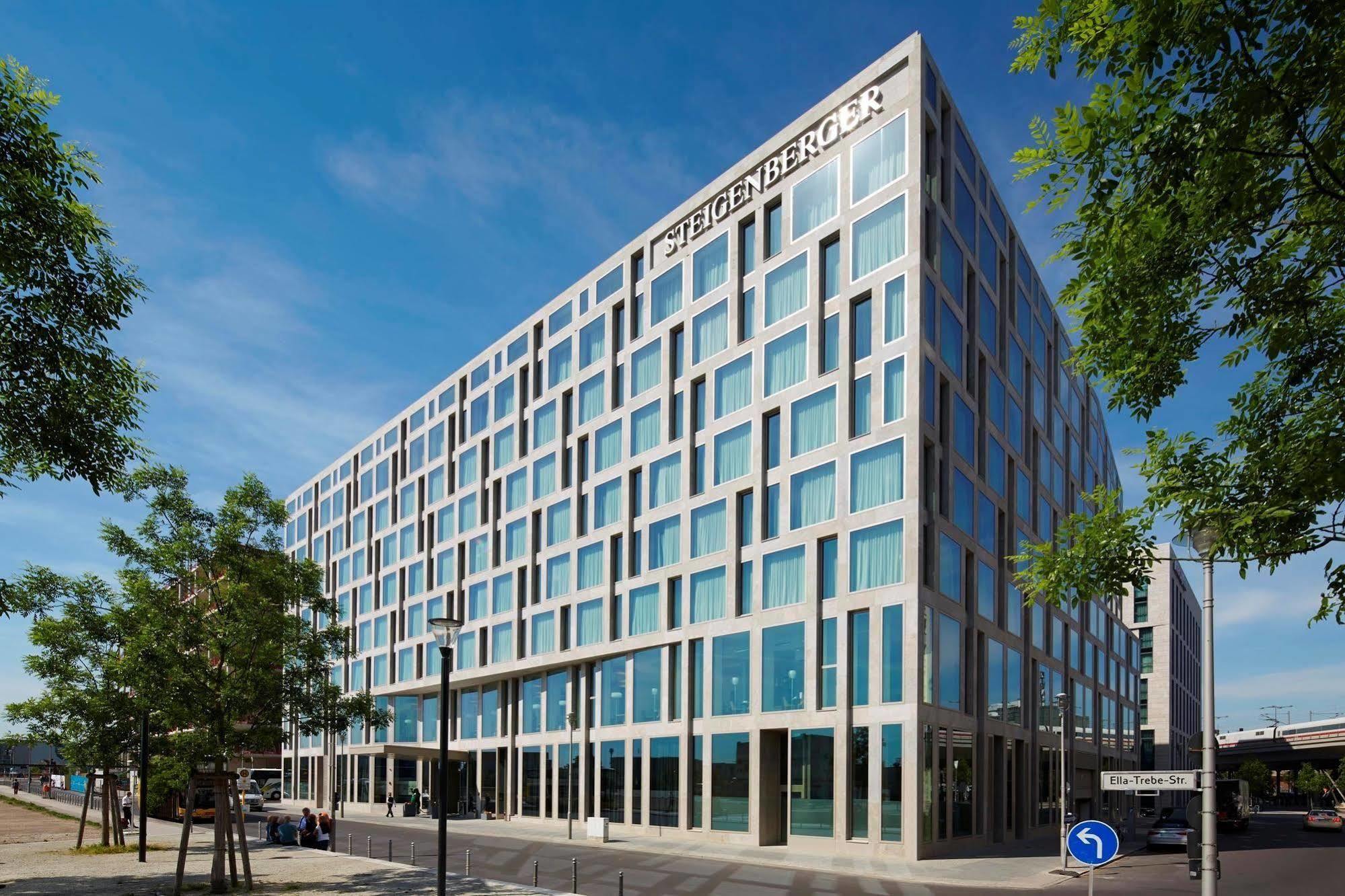 Steigenberger Hotel Am Kanzleramt Βερολίνο Εξωτερικό φωτογραφία The photo shows a modern building with a distinctive facade featuring a grid of large windows. The architecture appears contemporary, characterized by clean lines and a minimalist design. The building is situated in an urban setting, surrounded by gr