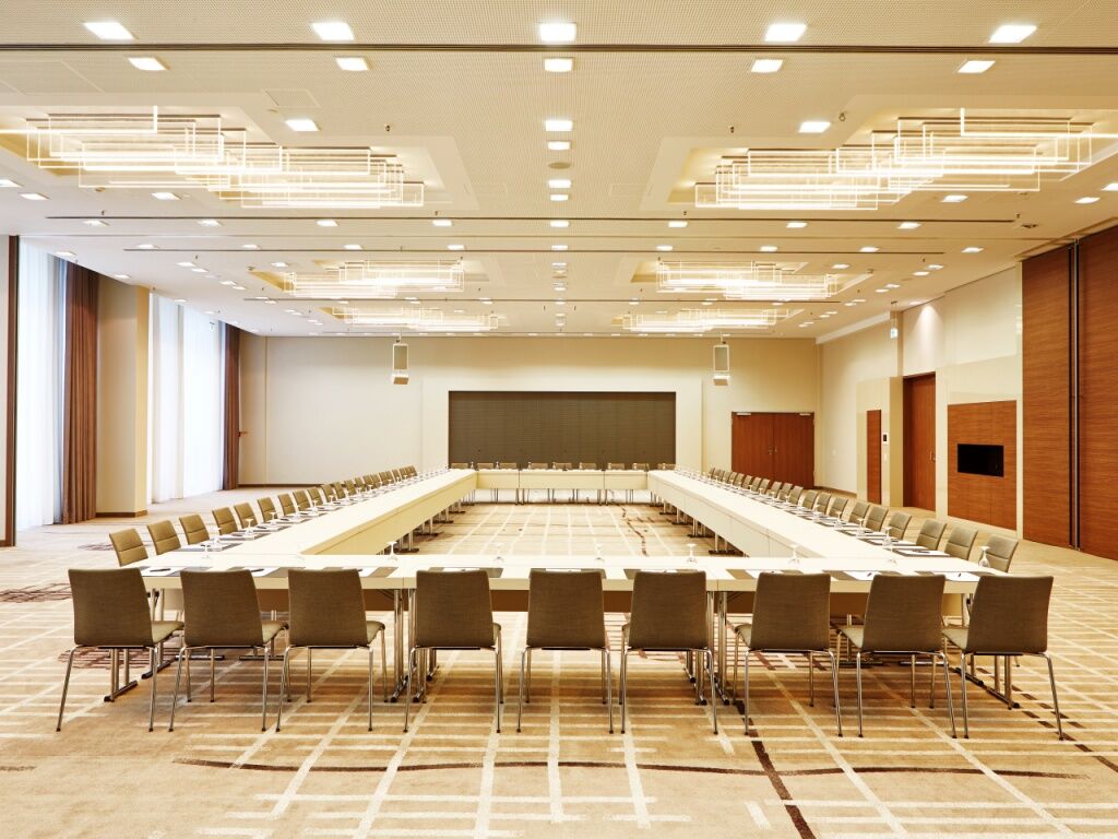 Steigenberger Hotel Am Kanzleramt Βερολίνο Εξωτερικό φωτογραφία The photo shows a large, modern conference room designed for meetings or presentations. It features a long, rectangular table set up in the center, surrounded by multiple chairs. The room is well-lit with contemporary lighting fixtures on the ceiling